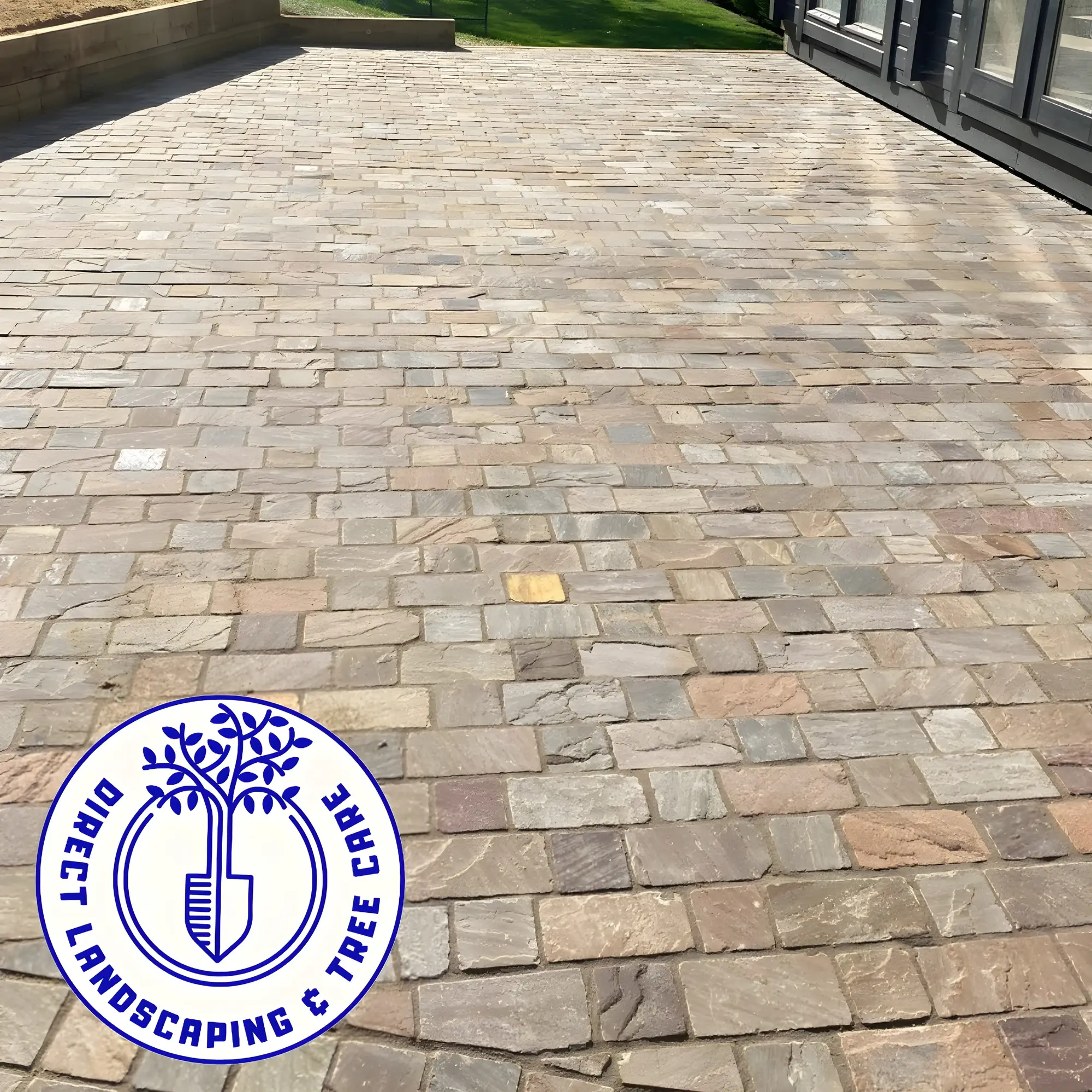 Driveway laid in tumbled block paving setts running up to a house